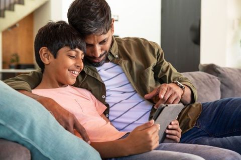 Father and son bonding with tablet in cozy living room