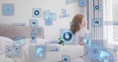 Senior blonde woman relaxing with augmented reality interface in bright bedroom blue overlays