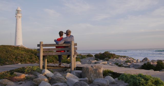 Senior Couple Sitting on Bench near Lighthouse by the Ocean - Download Free Stock Images Pikwizard.com