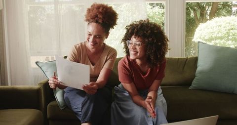 African American women reviewing documents and smiling while collaborating from home