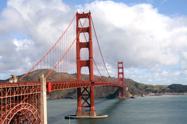 Golden Gate Bridge shown against blue water and hills in the background; useful for travel blogs, tourism promotion, educational content on landmarks, San Francisco city guides, architectural studies, and USA-themed projects.