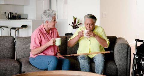 Happy Senior Lesbian Couple Enjoying Coffee on Cozy Couch
