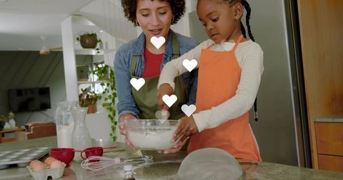 Caregiver and child baking together on kitchen island, stirring batter with heart overlays