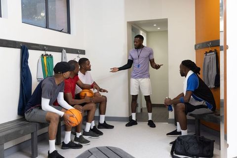 African american basketball coach delivering motivational team talk in locker room