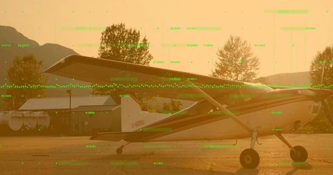 Single-Engine Propeller Plane Sitting on Apron at Sunset with Green Digital Data Overlay