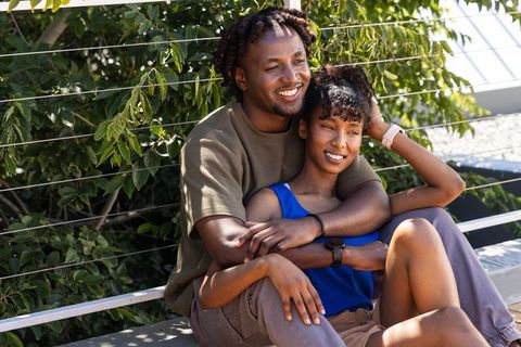 African american couple embracing on rooftop bench enjoying sunny terrace romance