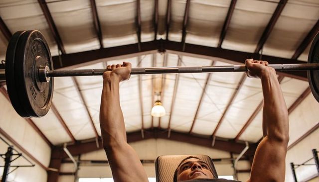 Barbell bench press showing upper-body strength focused athlete pressing heavy weight