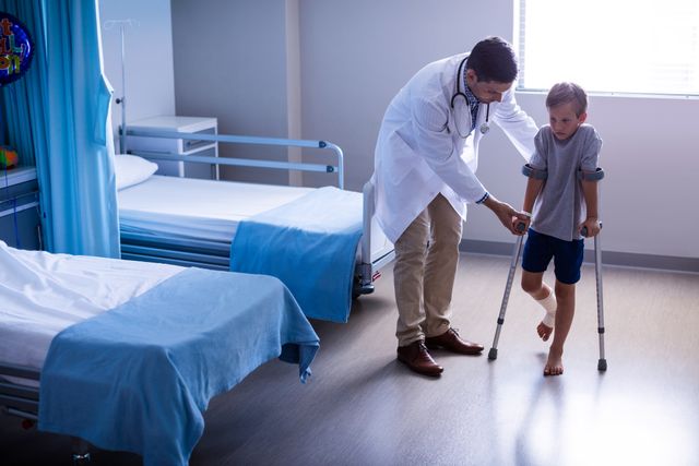 Doctor Assisting Injured Boy with Crutches in Hospital Room - Download Free Stock Photos Pikwizard.com