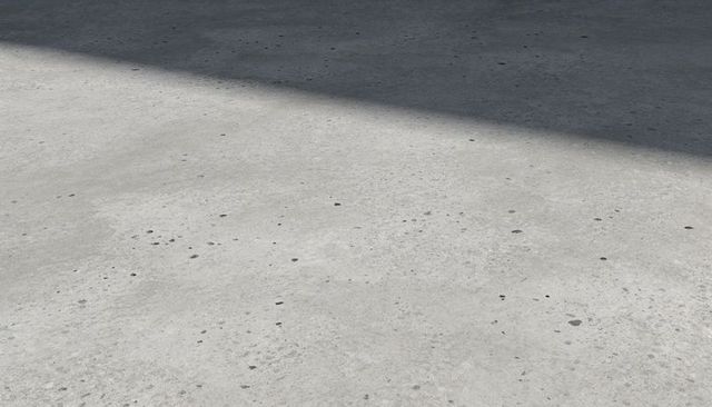 Sunlit light-gray concrete slab with speckled texture and diagonal shadow for backgrounds