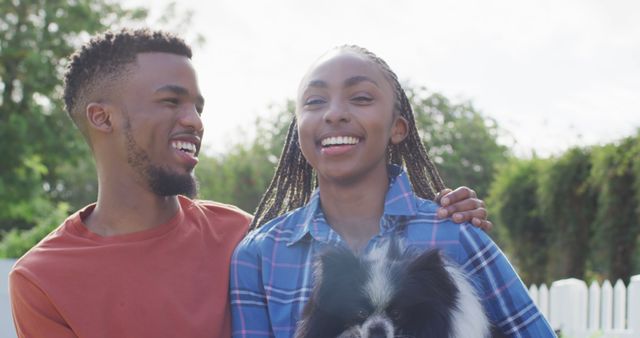 Happy african american couple with dog in backyard. Lifestyle, relationship, spending free time together concept.