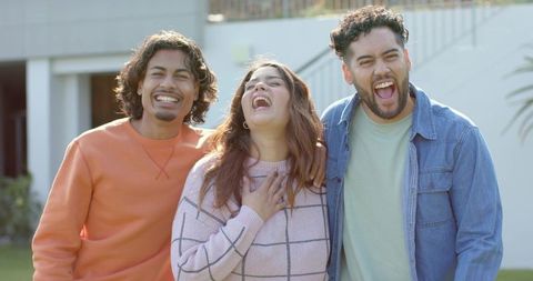 Multiethnic friends laughing together on front porch, candid casual lifestyle moment