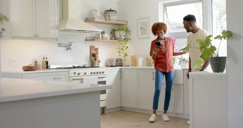 Couple using smartphone in sunlit kitchen animating recipe card for dinner inspiration