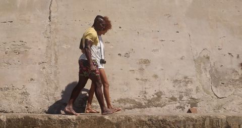 Joyful Couple Strolling by Sunlit Stone Wall - Download Free Stock Images Pikwizard.com