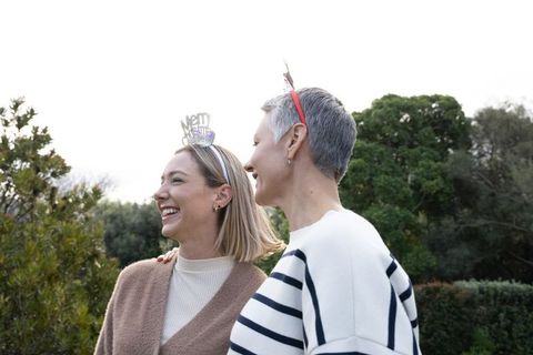 Smiling multigenerational women celebrating outdoors with festive headbands and cozy sweaters