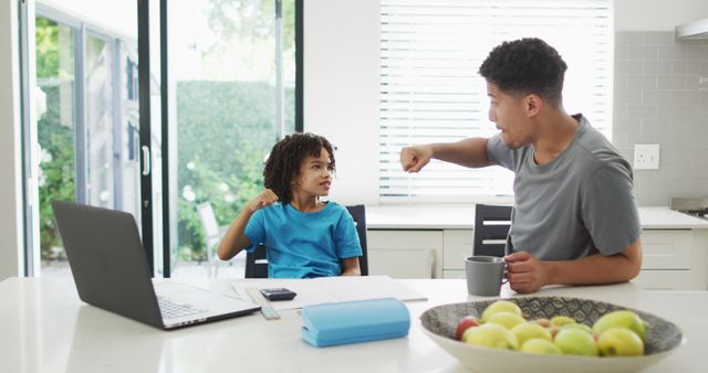 Happy biracial man and his son doing homework together, fistbumping - Download Free Stock Photos Pikwizard.com