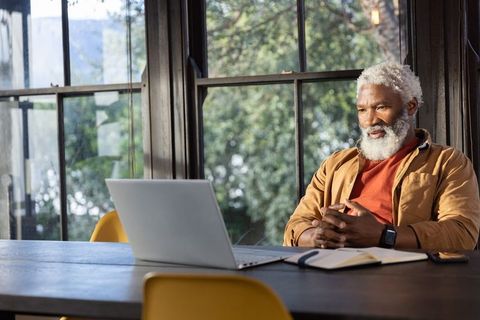 Senior african american man working remotely at laptop in bright home office