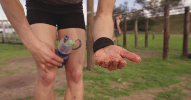 A Caucasian adult is displaying an injured palm while holding a water bottle, with copy space. Indicative of a sports injury, the focus on the hand suggests a recent fall or accident during exercise.