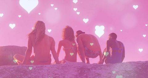 Group of Friends Relaxing on Rocky Outcrop at Sunset with Heart Bokeh