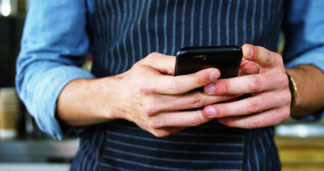 Barista with apron texting on smartphone in coffee shop - Download Free Stock Images Pikwizard.com