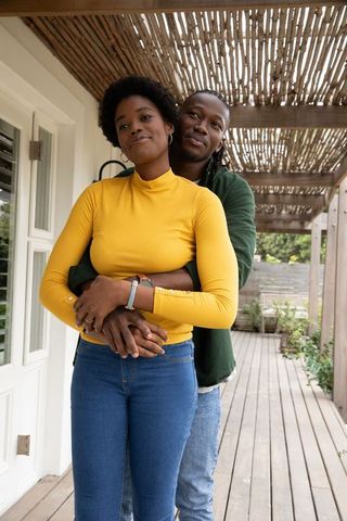 Loving Couple Embracing on Wooden Deck Under Pergola