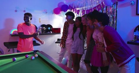 Multicultural Friends Posing and Smiling Around Pool Table at Neon Birthday Celebration