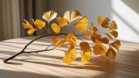 Ginkgo branch with golden leaves on wooden surface