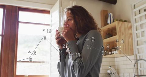 Woman Sipping Coffee in Sunlit Kitchen with Rustic Decor