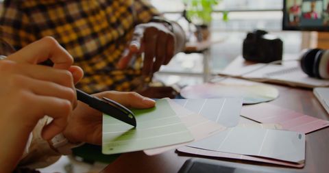 Creative designers collaborating with color swatch in modern office