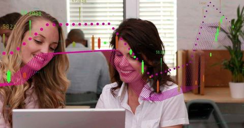 Female colleagues collaborating over laptop reviewing financial charts and data analytics