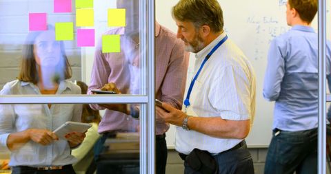 Team brainstorming with sticky notes on glass wall