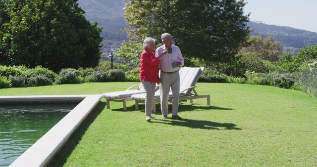 Happy caucasian senior couple walking in sunny garden holding hands carrying cups and talking - Download Free Stock Photos Pikwizard.com