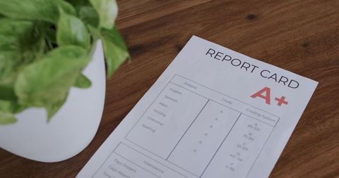 Report card a+ on wooden desk with potted plant, minimalist workspace and academic success