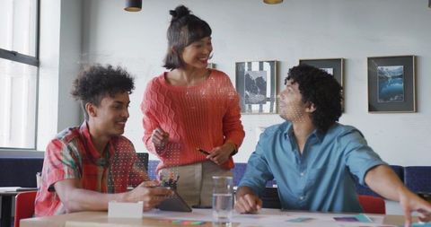 Young creative team collaborating on design using tablet and color swatches in modern coworking spac