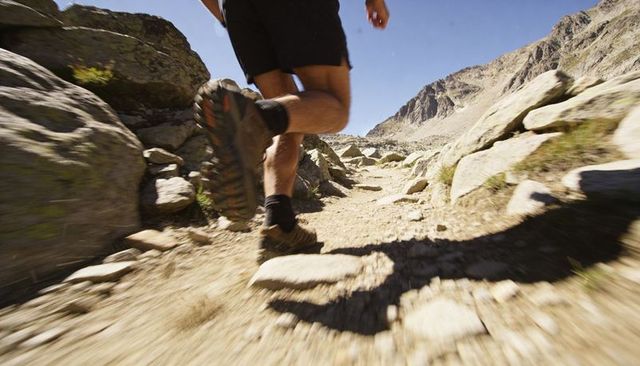 Powering up rocky mountain trail running male wearing black shorts and hiking shoes