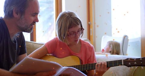 Father Guiding Daughter in Acoustic Guitar Lesson at Home