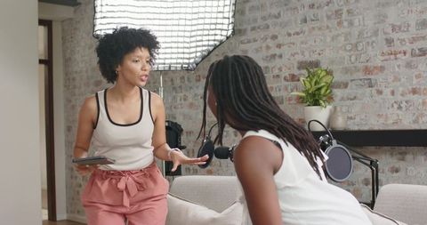 African american women hosting podcast in modern living room studio recording conversation