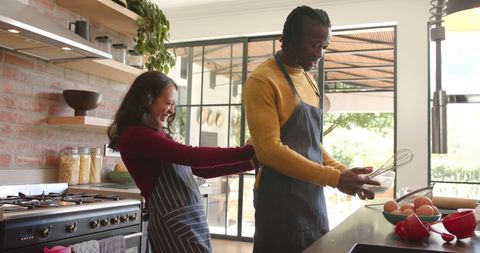 Cheerful couple baking together in bright modern kitchen