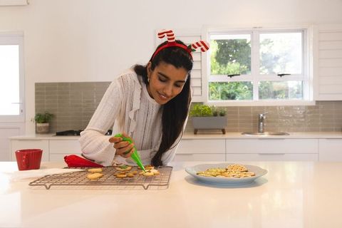 Festive Cookie Decorating Woman with Antler Headband in Kitchen