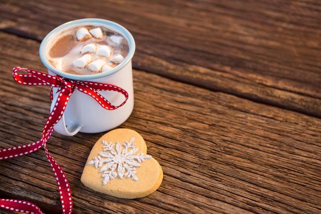 Cup of coffee with sugar cube and heart shape cookies tied with red ribbon on wooden plank