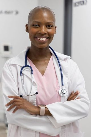Confident african american female doctor standing arms crossed wearing stethoscope white coat