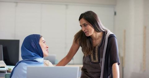 Indian women colleagues collaborating in office wearing kurta and headscarf