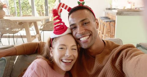 Joyful couple celebrating holidays with festive headbands at home