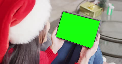 Festive Woman in Santa Hat Using Tablet with Green Screen During Video Call