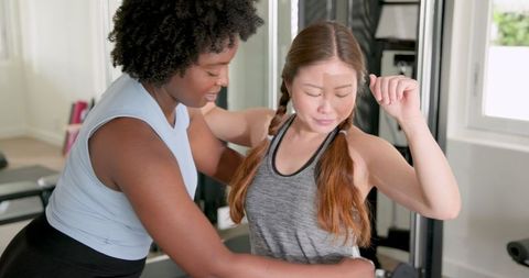 Diverse Women Engaging in Friendly Fitness Coaching at Gym