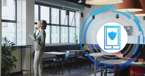 Woman standing by coworking windows talking on headset and smartphone with security overlay