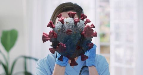 Clinician holding oversized virus model demonstrating infection control and education