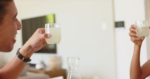African american couple clinking lemonade glasses in sunlit minimal modern living room