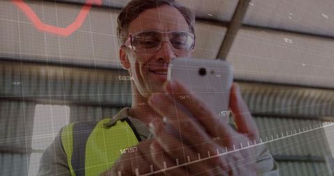 Mature industrial worker checking smartphone with augmented data overlays in warehouse