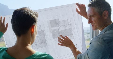 Architectural Team Analyzing Blueprint Planning at Office