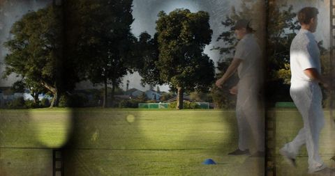 Grainy vintage cricket practice in park with bowlers in white kits and film-strip overlay